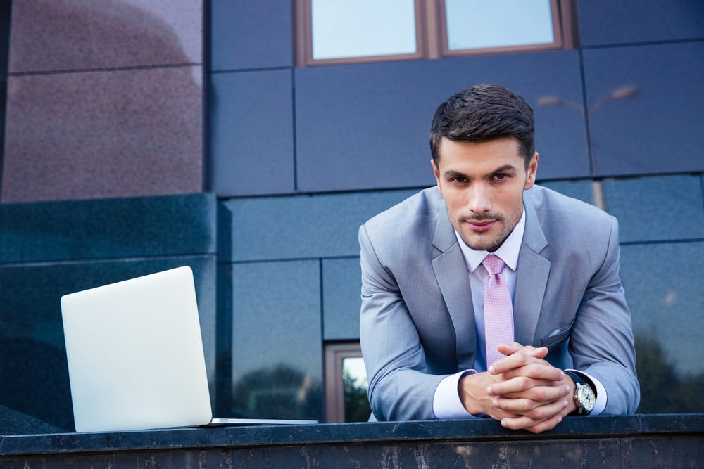 Portrait of a confident businessman with laptop computer outdoors. Looking at camera Portrait of a confident businessman with laptop computer outdoors. Looking at camera